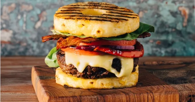 A delicious burger topped with pineapple, crispy bacon, and melted cheese, showcasing a unique flavor combination ground meat ideas