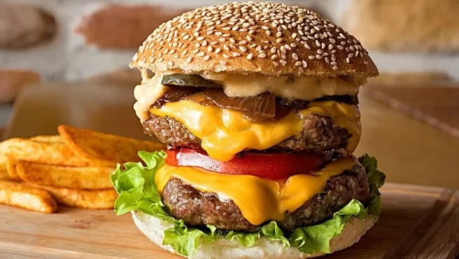 A large cheeseburger topped with melted cheese and fresh lettuce, showcasing its delicious layers and appetizing appearance dishes made with hamburger meat