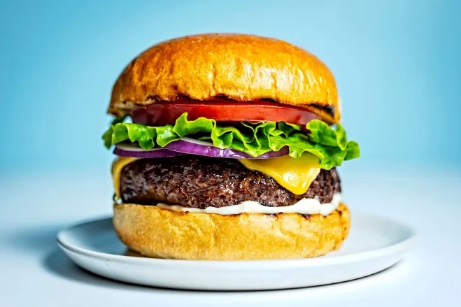 1. A hamburger topped with lettuce, tomato, and cheese, served on a white plate: dishes made with hamburger