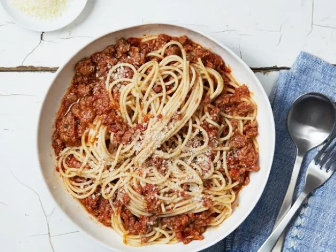 A bowl of spaghetti topped with rich meat sauce, garnished with herbs, ready to be enjoyed Cook with Ground Beef