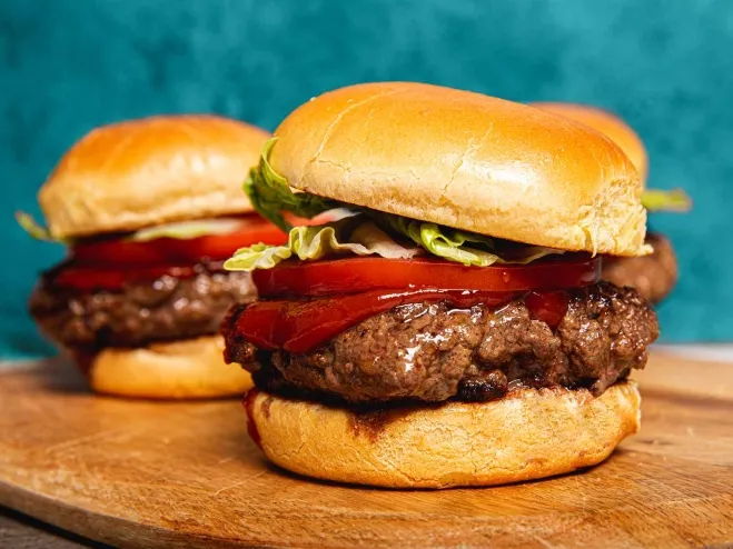 Three delicious hamburgers arranged neatly on a rustic wooden cutting board, showcasing their appetizing toppings and buns beef hamburger recipes for dinner