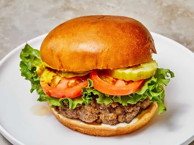 1. A hamburger topped with lettuce, tomato, and pickles served on a white plate, showcasing a delicious mealground mince recipes