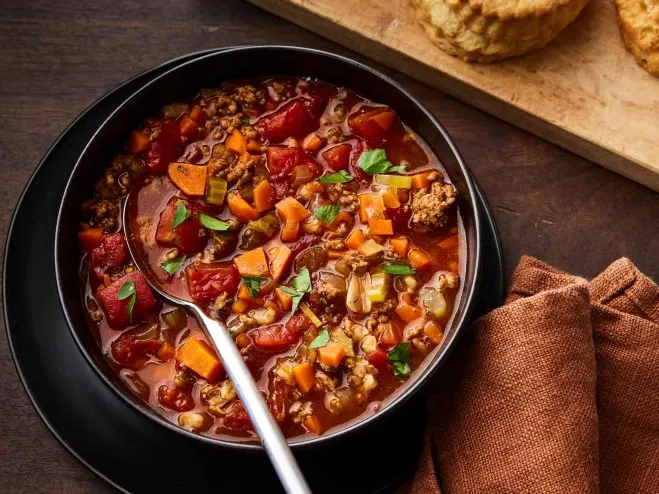  A bowl of hearty chili accompanied by freshly baked biscuits, showcasing a comforting and delicious meal recipes made with hamburger meat