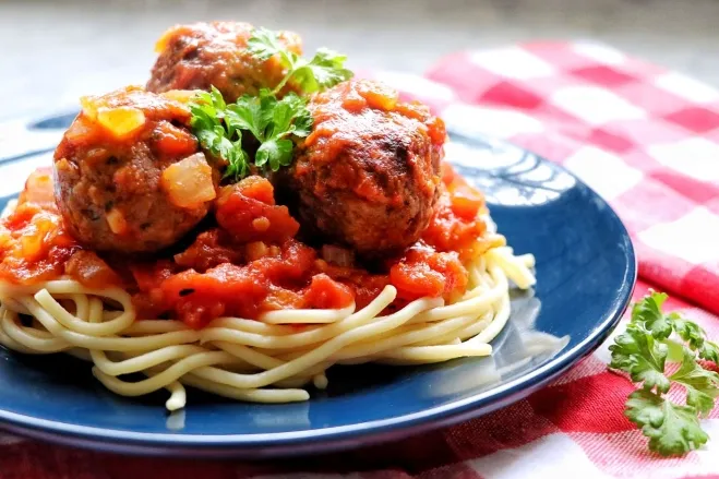 A plate of spaghetti topped with meatballs, garnished with parsley and served with a side of marinara sauce recipes containing ground beef