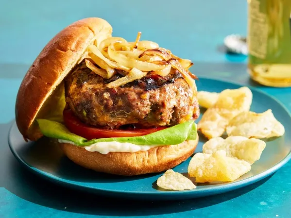 1. A hamburger topped with onion and cheese, served on a blue plate, showcasing a delicious meal presentation dishes to make with hamburger