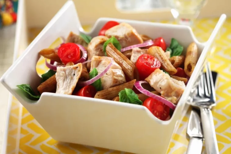 A bowl of pasta featuring chicken, fresh tomatoes, and onions, beautifully arranged for a delicious meal healthy lunch suggestions