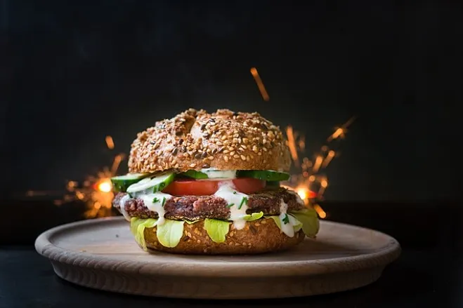 A delicious hamburger topped with cheese and tomatoes, served on a rustic wooden plate hamburger recipes for supper