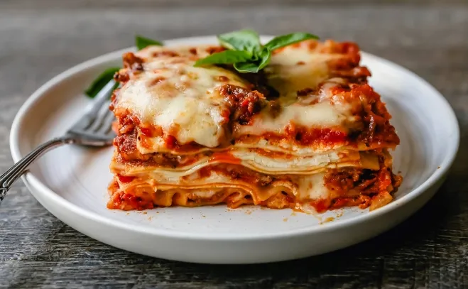  A slice of lasagna served on a white plate, showcasing layers of pasta, cheese, and rich tomato sauce ground beef dinner ideas