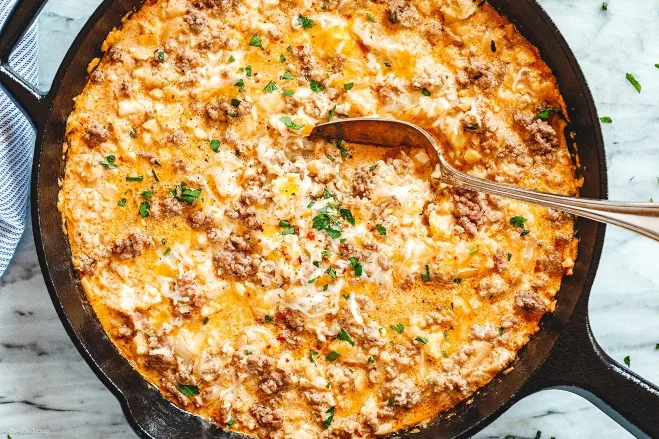 A cheesy egg casserole bubbling in a skillet, showcasing a golden, savory dish ready to be served supper ideas with hamburger meat