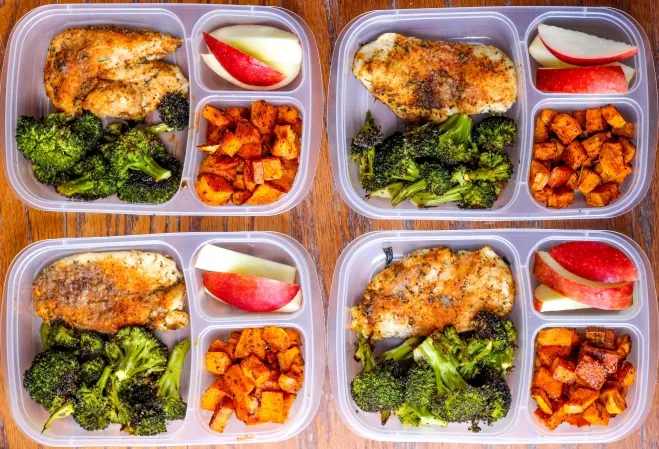  Four plastic containers filled with chicken, broccoli, apples, and potatoes arranged neatly on a surface lunchtime ideas