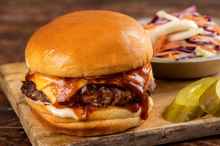 1. A delicious hamburger topped with BBQ sauce and pickles, presented on a rustic wooden cutting board hamburger recipes