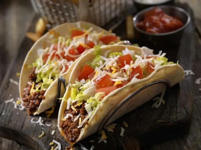 Two delicious tacos filled with meat and cheese, elegantly presented on a rustic wooden board dinner meals with ground beef 