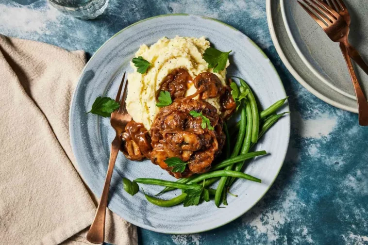 A plate of chicken topped with mushroom gravy, accompanied by fresh green beans, showcasing a delicious meal ground beef dishes for dinner