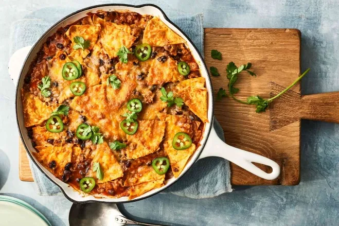 1. A skillet filled with delicious Mexican nachos topped with cheese, jalapeños, and fresh toppings, ready to be servedmeals made with hamburger meat