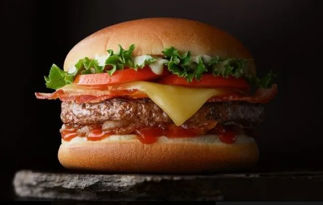 A delicious hamburger topped with cheese, crispy bacon, and fresh tomato, served on a toasted bun dishes made with hamburger meat