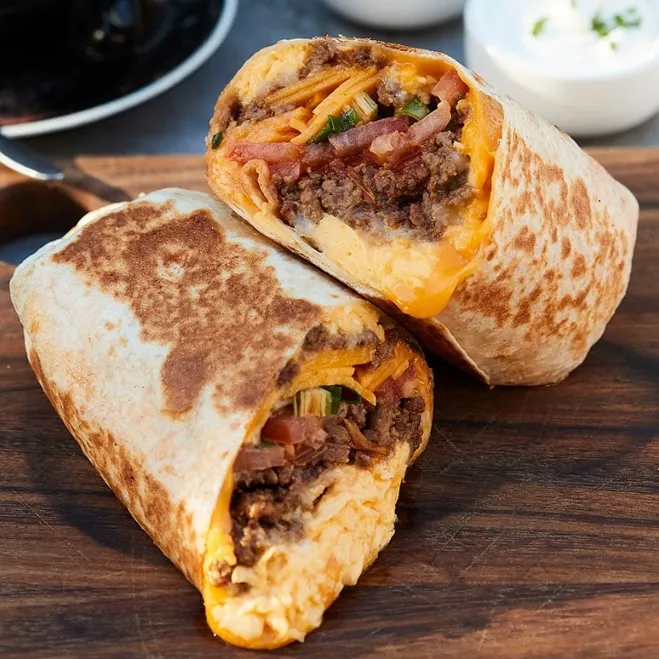 1. A burrito filled with cheese and meat rests on a wooden cutting board, ready to be served with recipes to make with ground beef