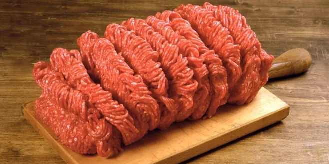 1. A pile of raw ground beef rests on a wooden cutting board, showcasing its rich red color and fresh texturebeef ground meat recipes