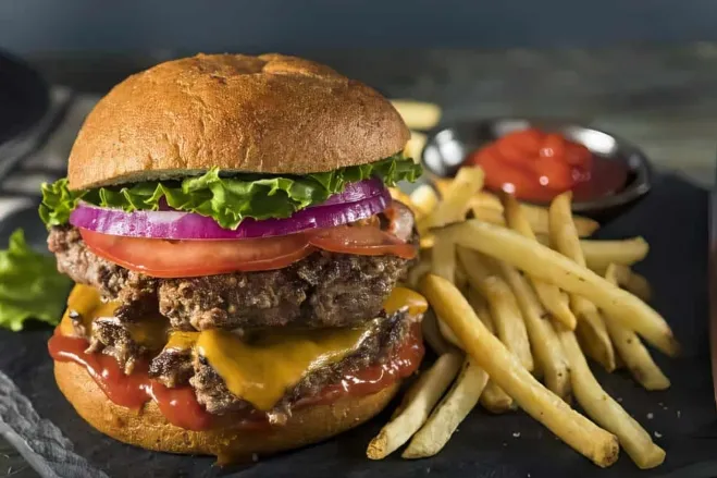 A delicious hamburger accompanied by crispy french fries and golden onion rings on a plate chop meat dinner ideas