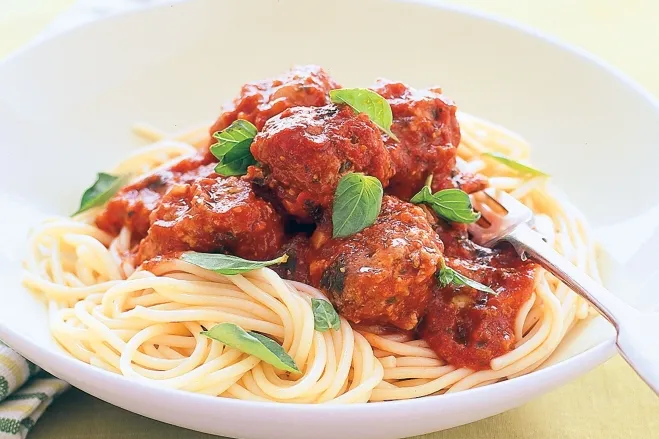  A plate of spaghetti topped with meatballs and rich tomato sauce, garnished with herbs for added flavor ground meat dishes