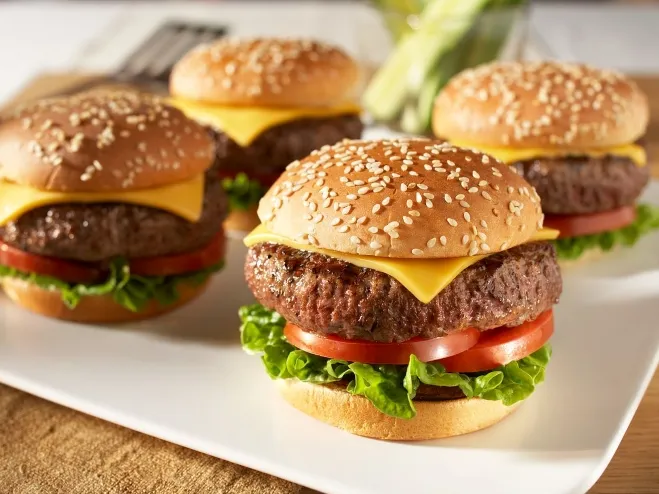 1. Four hamburgers topped with lettuce and tomato arranged neatly on a white platemeals made with hamburger meat