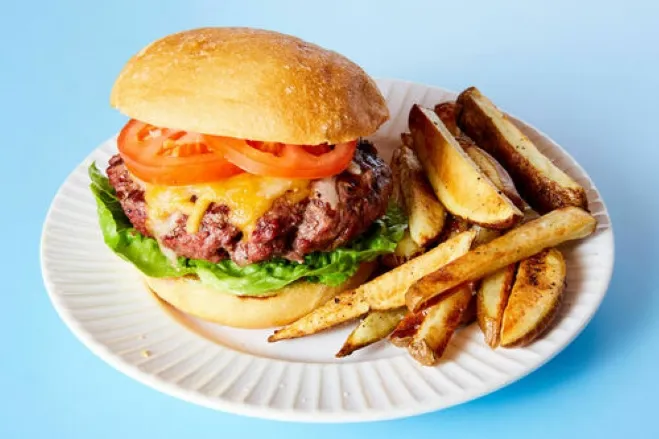 A delicious hamburger topped with cheese, tomato, and lettuce, served on a plate, ready to be enjoyed hamburger dishes for supper