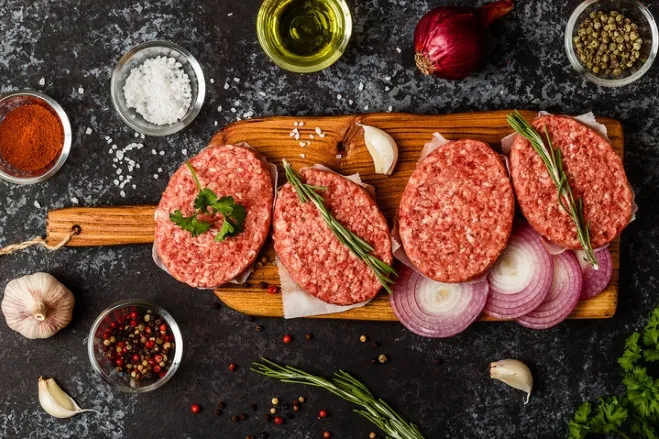 .Raw meat on a wooden cutting board, surrounded by fresh herbs and an array of colorful spices dinner ideas using ground beef