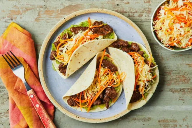  A plate featuring three tacos filled with meat and fresh vegetables, ready to be enjoyed dinner ideas using ground beef