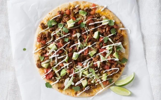 A delicious Mexican pizza topped with ground beef, fresh avocado slices, and a wedge of lime for added zest dishes made with hamburger meat