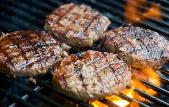 1. Three hamburgers sizzling on a grill, showcasing a delicious cooking process with smoke rising ground hamburger meat