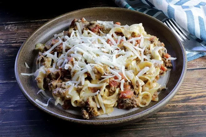 A plate of pasta topped with savory meat and melted cheese, showcasing a delicious Italian dish meals to cook with ground beef