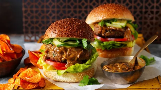 Two delicious burgers served with crispy chips and a side of dipping sauce on a wooden table hamburger recipes for supper