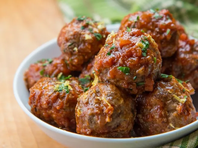  A bowl filled with meatballs topped with rich sauce and garnished with fresh herbs ground beef dinner ideas