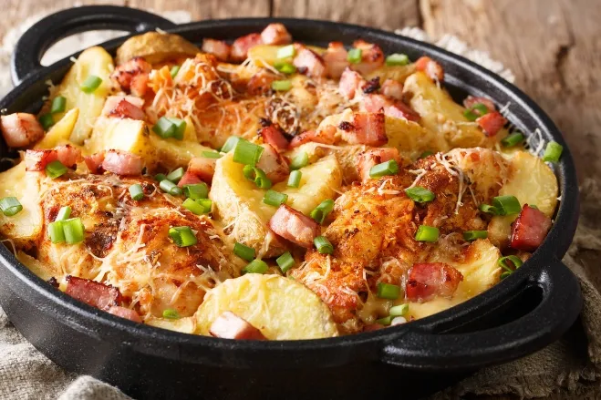 A skillet filled with chicken and potatoes, garnished with fresh green onions, ready to be served dinner with hamburger meat ideas