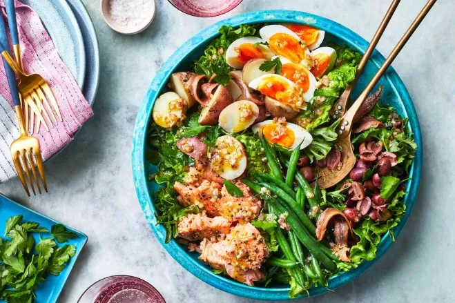 A blue bowl containing a fresh salad topped with sliced eggs, showcasing vibrant colors and textures healthy lunch suggestions