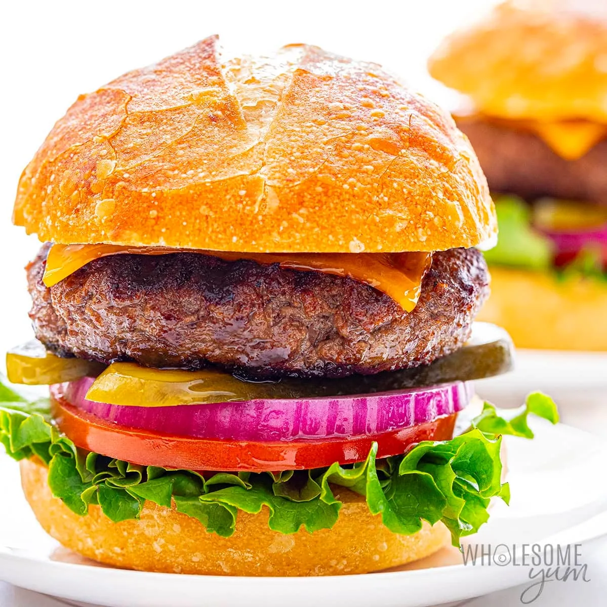 A delicious hamburger served on a white plate, garnished with fresh lettuce and tomato, ready to be enjoyed hamburger recipes for supper